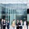 Groups of contemporary business people in formalwear standing by modern building and consulting outdoors